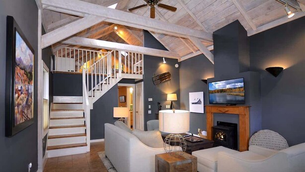 A spacious living room with a staircase, a fireplace, and a television. - 305 Third Street (Crested Butte)