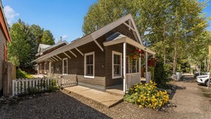 Une maison en bois à deux étages, dotée d’un porche couvert et d’une allée gravillonnée.