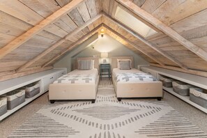 A cozy attic bedroom with two beds, a nightstand, and storage bins. - 305 Third Street (Crested Butte)