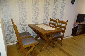 Enjoy meals in this cozy dining area with a wooden table, comfortable chairs, and a TV for entertainment.