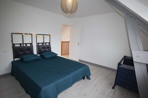A bedroom with a bed, a desk, and a staircase.