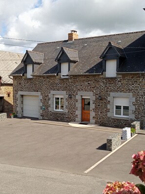 A stone building with a garage, a wooden door, and a small window.