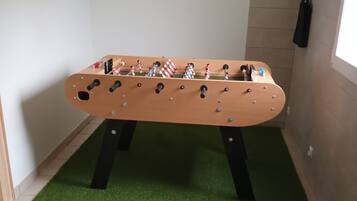 Enjoy a game of foosball in this room's corner, featuring a table with a wooden surface and metal rods.