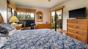 Un dormitorio con cama, televisión, cómoda, escritorio y balcón.