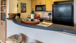 Una cocina moderna con una isla curvada, taburetes de madera y electrodomésticos integrados.