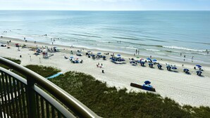 Een strand met parasols en mensen.
