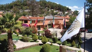 A building with a garden, flags, and a flagpole. - Hotel Arrecife de Coral (San Cristóbal de las Casas)