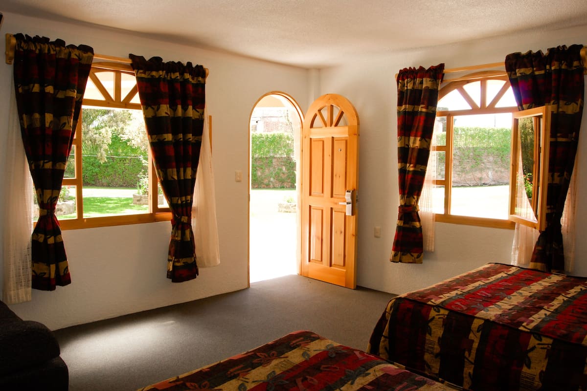 A room with two beds, a wooden door, and curtains on the windows.
