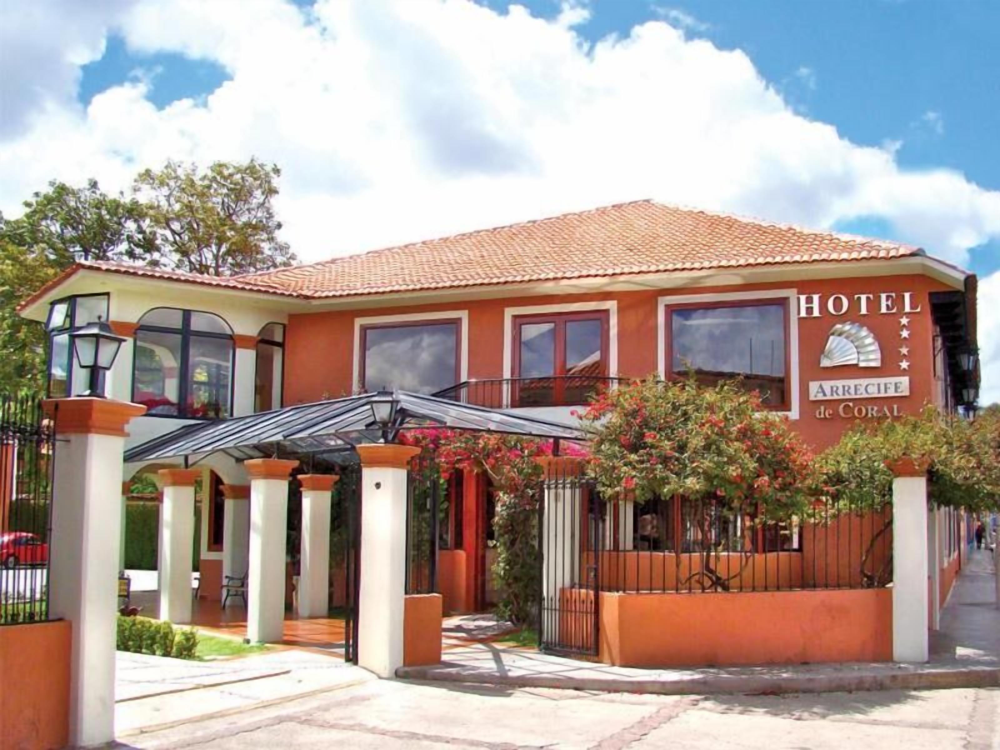 A hotel with a tiled roof, a covered entrance, and a sign that reads "HOTEL ARRECIFE de CORAL".