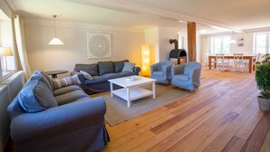 Ein geräumiges Wohnzimmer mit einer großen Couch, einem Couchtisch und einem Essbereich mit Tisch und Stühlen.