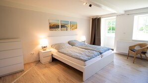 Ein Schlafzimmer mit Bett, Nachttischen, einem Sessel und Bildern an der Wand.