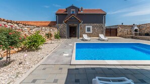 Ein Haus mit Schwimmbecken, Steinmauern und einer Steinterrasse.
