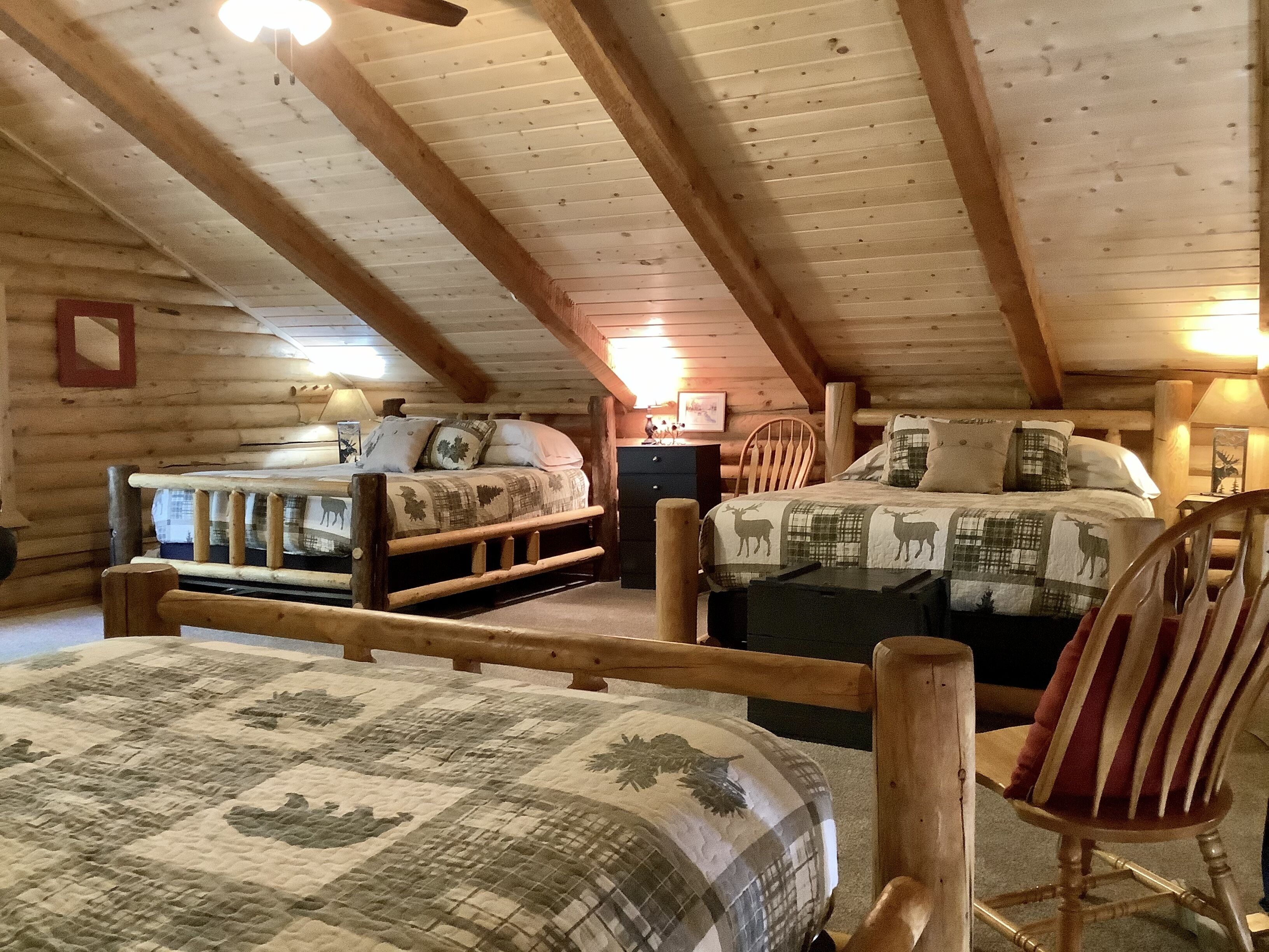 A log cabin bedroom with two beds, wooden beams, and a rustic decor.