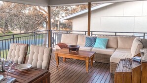 Un espacio al aire libre techado con mesa de madera, sillas y un sofá.