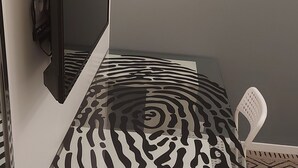 A small, modern room with a glass-top bed, a white chair, and a mounted TV. - Chambre Avec Douche Privée , Espace Cuisine (Deauville)