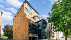 Un bâtiment moderne avec une façade en briques, de grandes fenêtres et une entrée en verre incurvée.