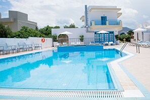 Alberca al aire libre, sombrillas en la alberca y camastros 