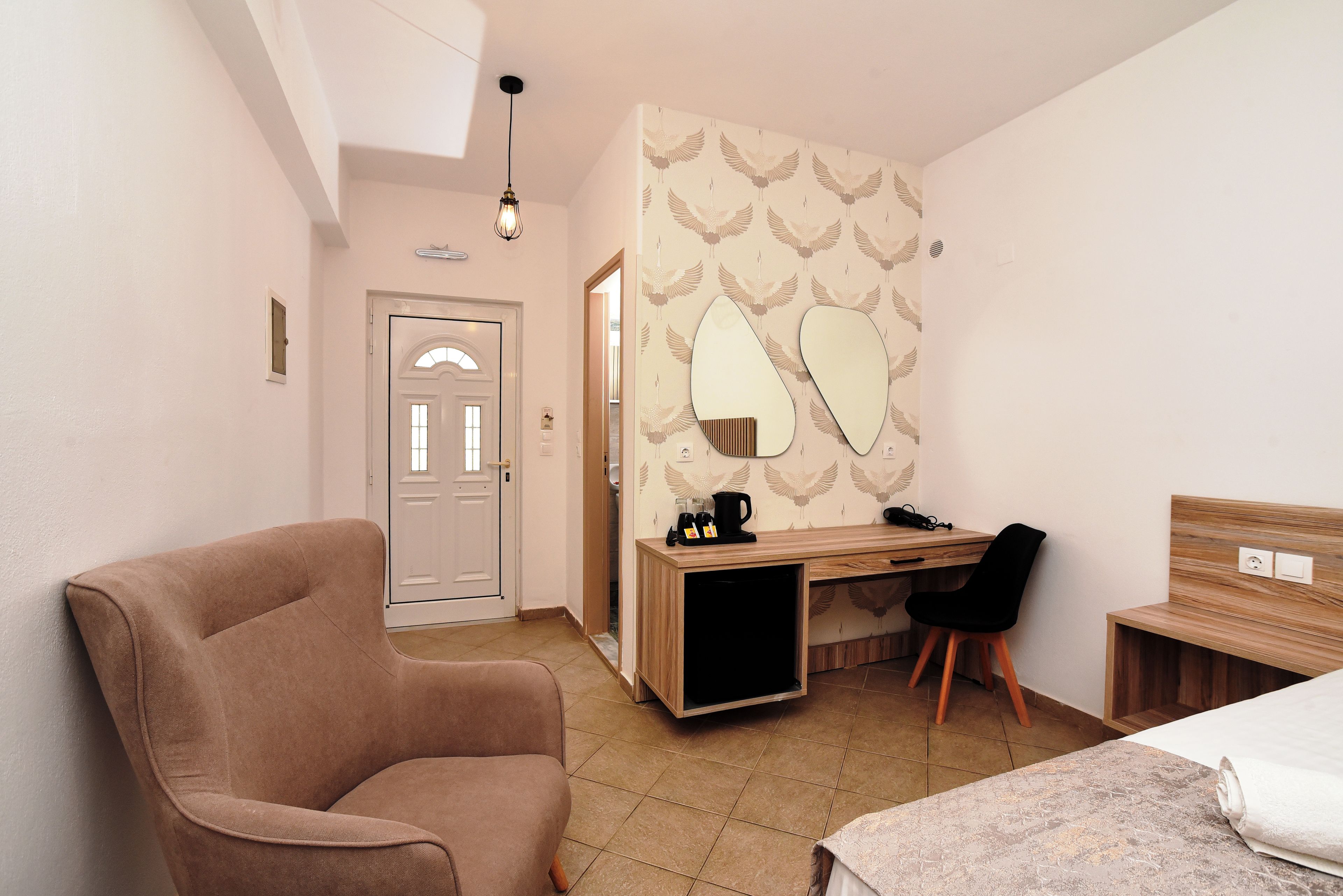 A bedroom with a bed, a desk, a chair, and a large mirror on the wall.