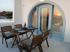 A wooden table with blue plates and wine glasses, set against a white wall with a blue door. - Two floor cycladic house (Naxos)