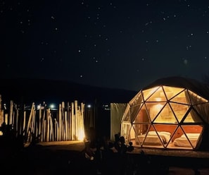 A dome-shaped tent with a warm interior light, set against a starry night sky. - Raices Glamping (Soyaniquilpan de Juárez)