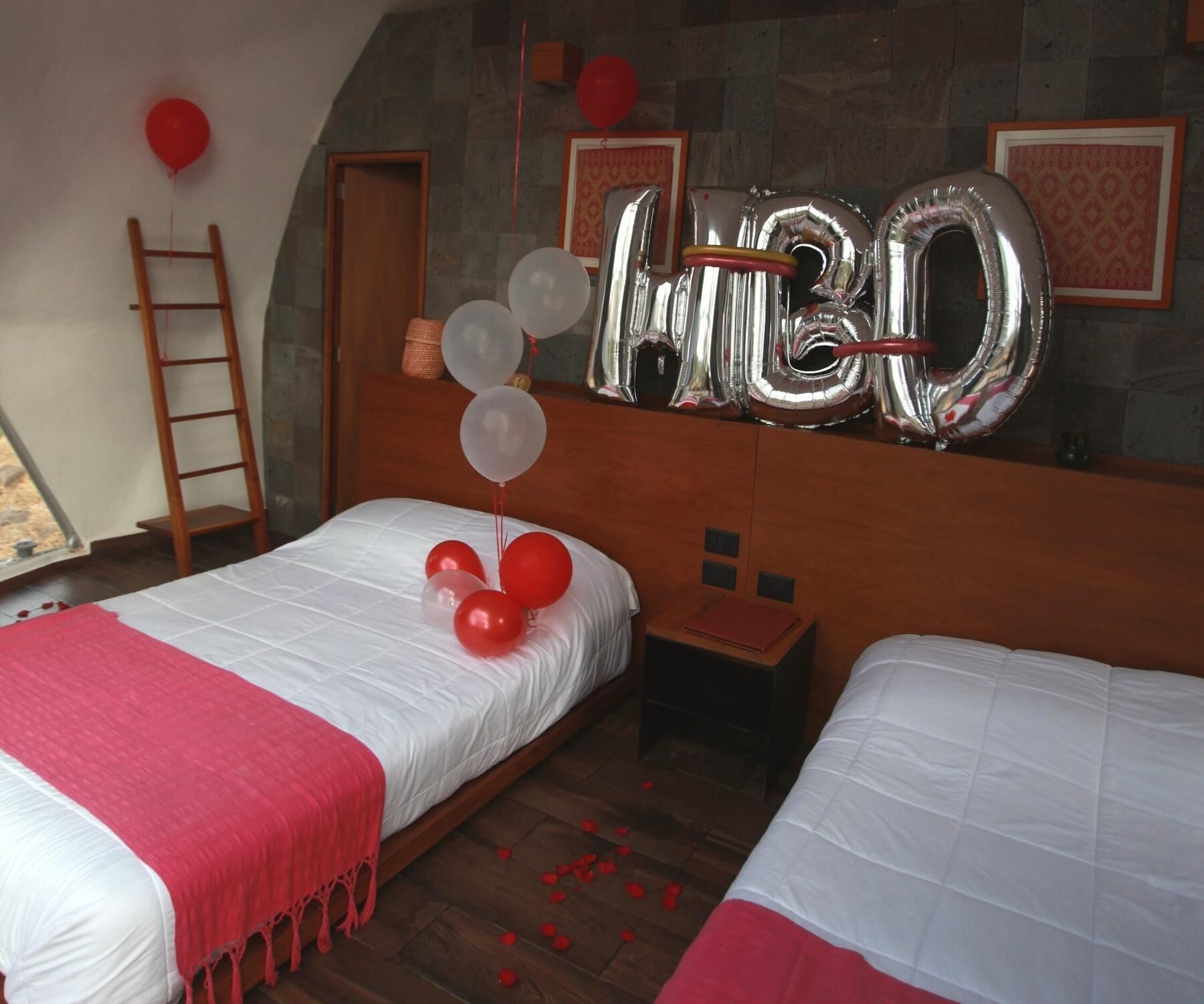A hotel room with two beds, a wooden ladder, and a large number '30' balloon decoration.