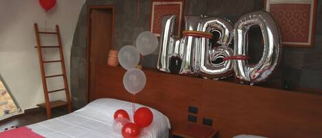 A hotel room with two beds, a wooden ladder, and a large number '30' balloon decoration.