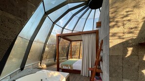 Une chambre avec une grande fenêtre, un lit en bois, une chaise en bois et une baignoire.