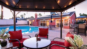 Un espacio al aire libre cubierto con piscina, asientos rojos y una mesa.
