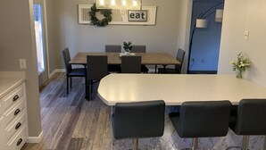 Una cocina moderna con comedor, que incluye una mesa de madera, sillas negras y un candelabro.