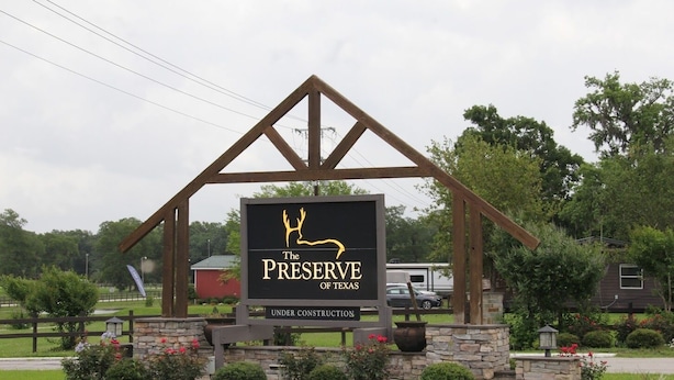 A sign for "The Preserve of Texas" with a deer logo, under construction, surrounded by greenery and a rural setting. - Family Vacation Cabin C3 (Cleveland)