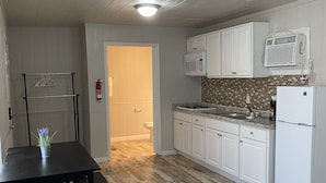 A kitchen with white cabinets, a microwave, a refrigerator, and a wooden floor. - Family Vacation Cabin C3 (Cleveland)