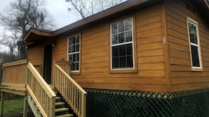 A two-story wooden cabin with a wooden deck and a staircase leading to the entrance. - Family Vacation Cabin C3 (Cleveland)