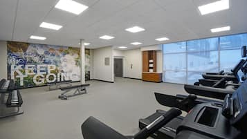 Ein Fitnessstudio mit Laufbändern, Ergometer und einer Wandmalerei mit motivierenden Sprüchen.
