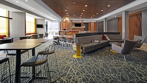 A modern hotel lobby with a central seating area, a bar, and a large TV screen. - Springhill Suites by Marriott Hartford Cromwell (Cromwell)
