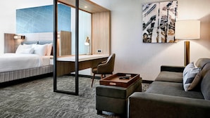 A hotel room with a bed, a desk, a sofa, and a large abstract painting on the wall. - Springhill Suites by Marriott Hartford Cromwell (Cromwell)