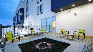An outdoor seating area with a fire pit, chairs, and a building with large windows and a flat roof. - Springhill Suites by Marriott Hartford Cromwell (Cromwell)