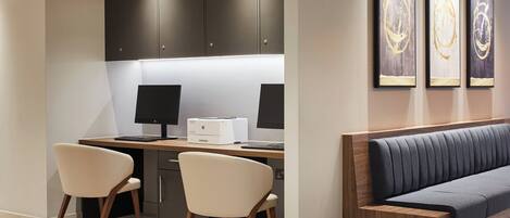 A modern office space with two desks, a printer, and a sofa.