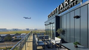 A Courtyard by Marriott hotel with a terrace overlooking a runway and airport. - Courtyard by Marriott London Heathrow Airport (Hayes)