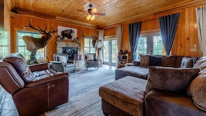 A spacious living room with leather sofas, a fireplace, and wooden walls. - The Lodge at Arcady Ridge Ranch, SWIM SPA + SAUNA sleeps up to 14! (Dubois)