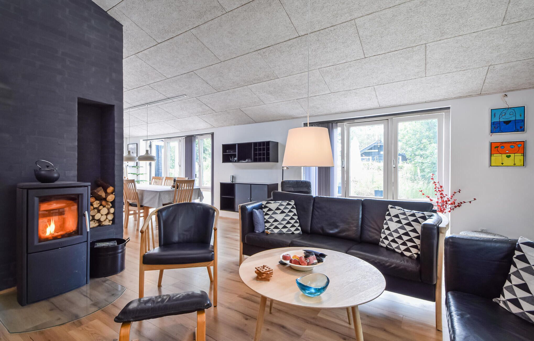 Un salon moderne doté d’une cheminée, d’un canapé, d’un coin repas et de grandes fenêtres.