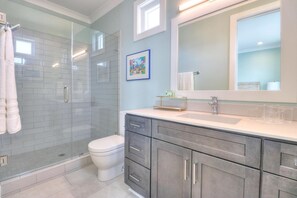 Une salle de bain moderne dotée d’une douche à parois de verre, de toilettes et d’un meuble-lavabo avec un grand miroir.