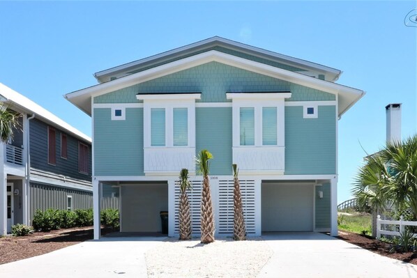 Une maison à deux étages avec un garage, une véranda et une petite allée.