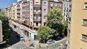 Um edifício residencial com vários andares, varandas, vista para a rua e carros estacionados.