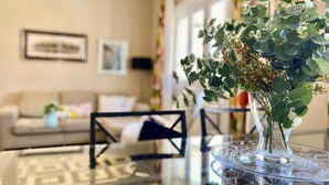 Uma sala de estar com uma mesa de vidro, um sofá e um vaso com folhagem verde.