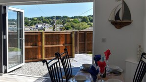 Eine offene Terrasse mit einem Esstisch für zwei Personen, einem Holzzaun und Blick auf ein Wohngebiet.