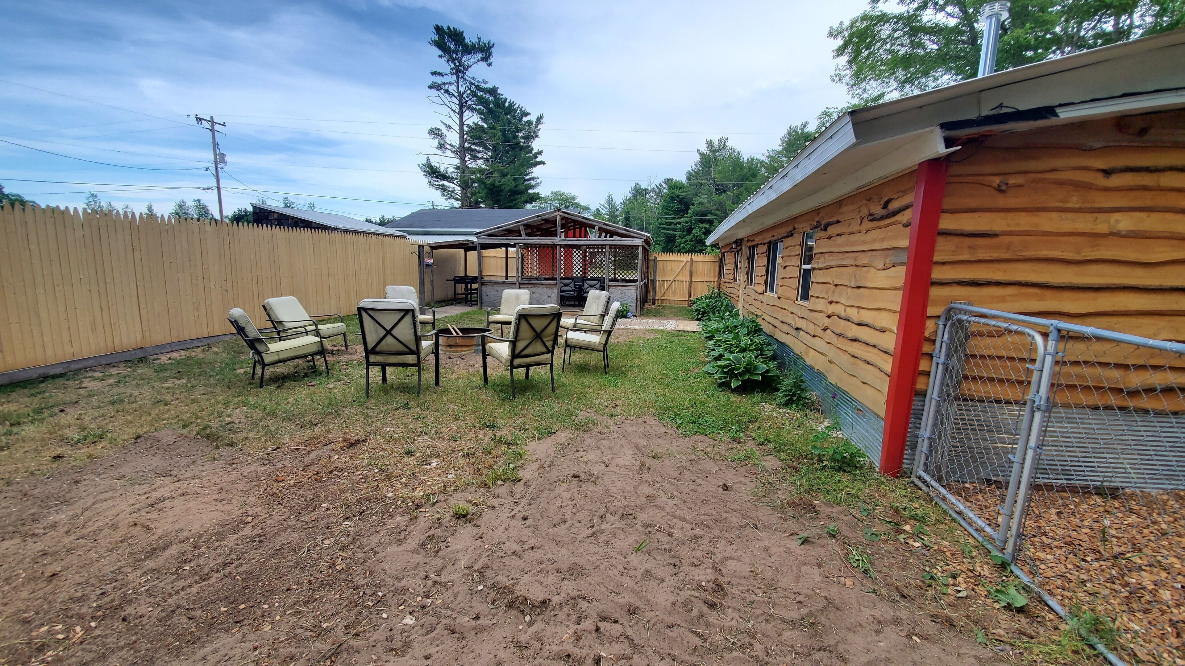 A backyard with a wooden deck, outdoor furniture, and a fenced area.