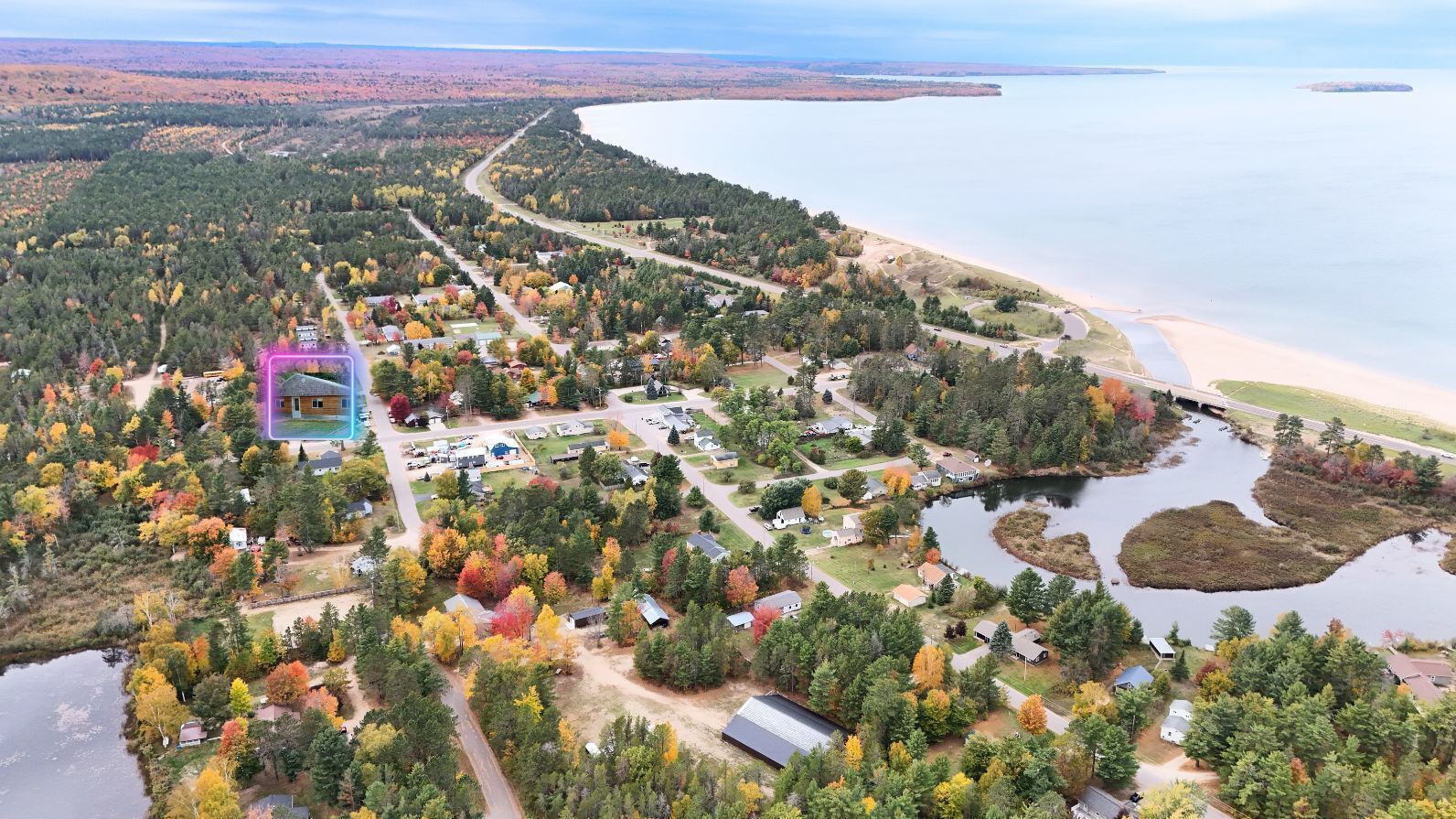 An aerial view of a coastal community with houses, roads, and a beach.
