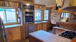 Une cuisine dotée de meubles en bois, d’un îlot central et d’appareils électroménagers en acier inoxydable, notamment un four à micro-ondes, un four et un lave-vaisselle.
