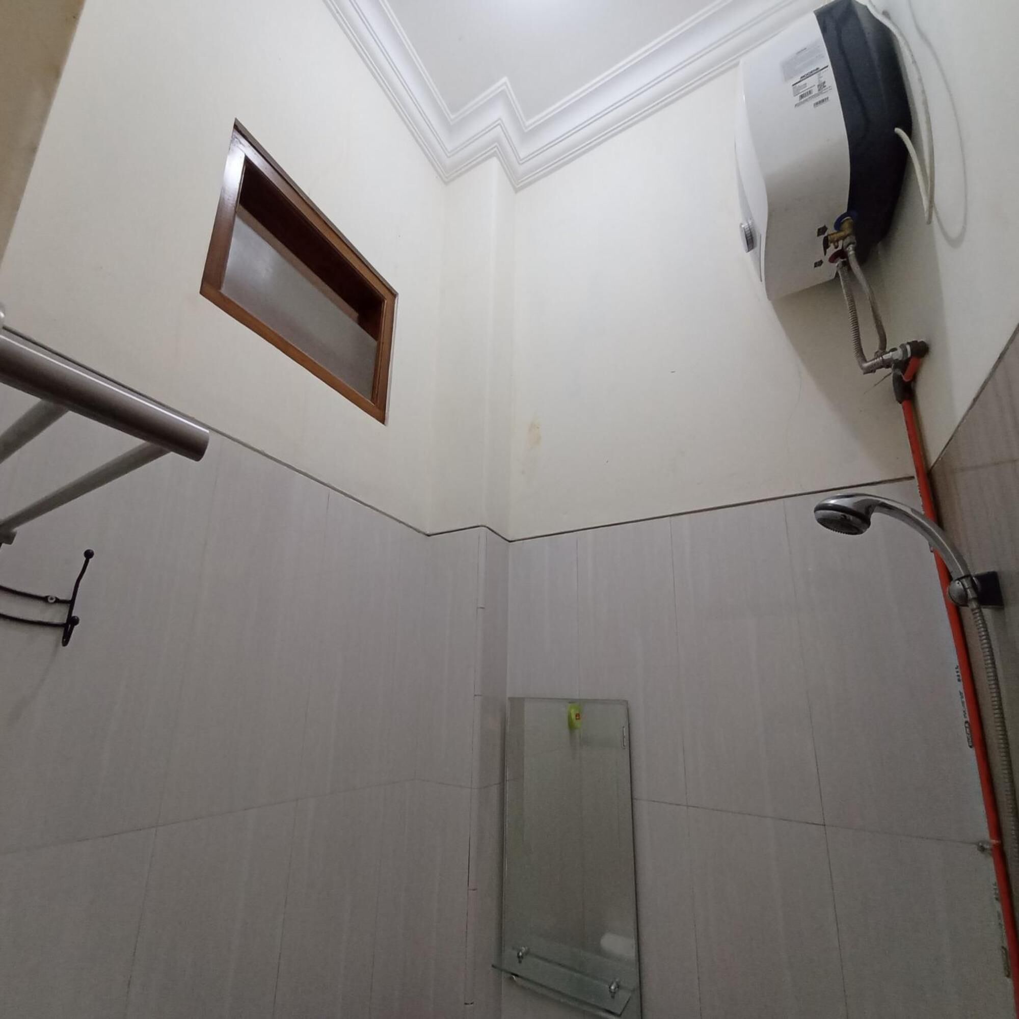A bathroom with a shower, a hand dryer, and a window.