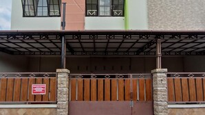 A two-story building with a green roof, a beige facade, and a brown gate. - OYO 3314 Syariah House (Purwokerto)